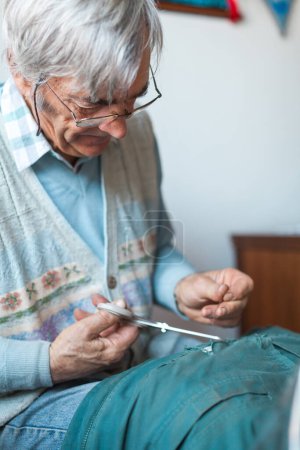 Photo for Retired Old Man Taylor Sewing and Repairing His Jacket By Hands at Home - Royalty Free Image