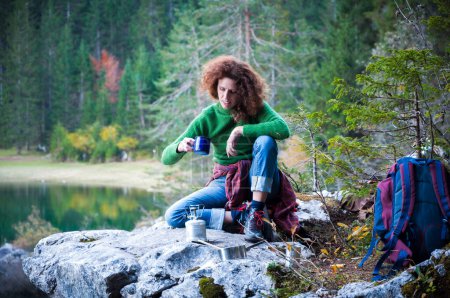 Foto de Mujer aventurera excursionista disfrutando de un café caliente en las montañas Entorno al aire libre Cerca de un lago alpino - Imagen libre de derechos