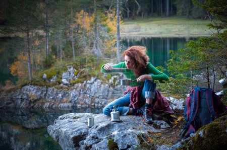 Foto de Cabello rizado Mujer adulta excursionista aventurero comiendo un auto preparado en el lugar Comida caliente en las montañas Ambiente al aire libre - Imagen libre de derechos