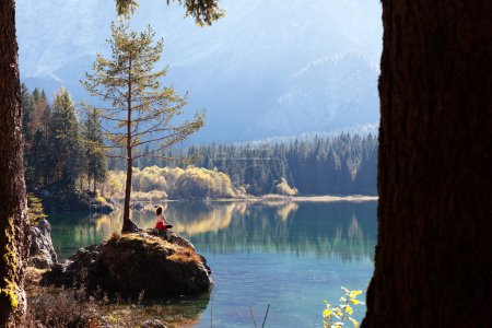 Foto de Senderista femenina encontró tranquilidad para la meditación cerca de un lago alpino de otoño - Imagen libre de derechos