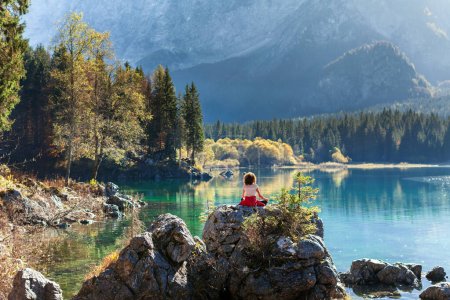 Foto de Meditación de la mujer adulta en el entorno natural de un lago alpino de otoño - Imagen libre de derechos