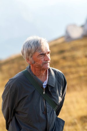 Photo for Thoughtful Senior Man Walking on a Countryside Meadow Portrait - Royalty Free Image