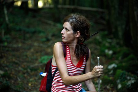 Femme randonneuse solo effrayée par un son regardant en arrière dans une forêt