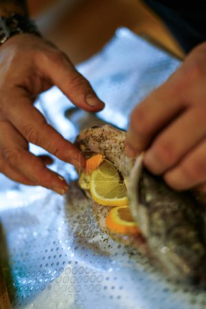 Preparing trouts with lemons, butter and green dill.