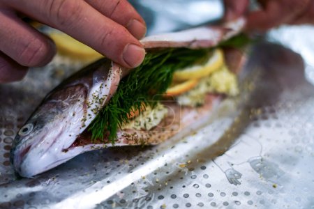 Preparing trouts with lemons, butter and green dill.