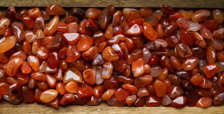 Carnelian stones on the wooden background.