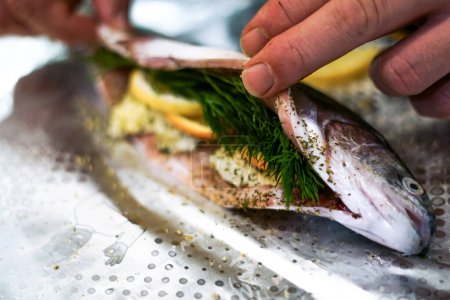 Preparing trouts with lemon butter and dill. 