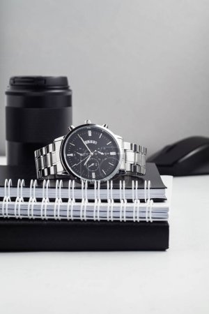 Foto de Reloj con portátil y lente de cámara en una mesa blanca - Imagen libre de derechos