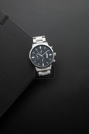 Téléchargez les photos : Carnet noir avec la montre argentée sur fond noir - en image libre de droit