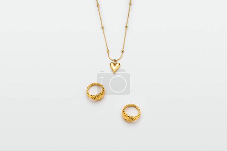 Téléchargez les photos : Bagues et collier doré de luxe avec pendentif coeur, plan studio - en image libre de droit