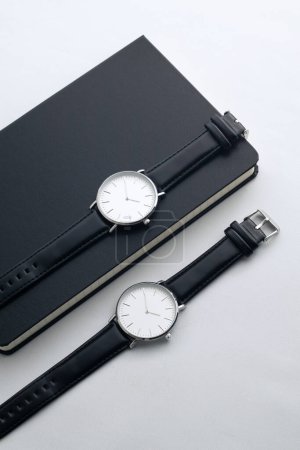 Foto de Relojes de cuero negro en escritorio blanco con cuadernos en blanco y negro - Imagen libre de derechos