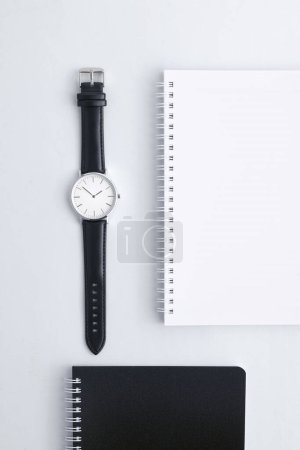 Téléchargez les photos : Montre en cuir noir sur bureau blanc avec cahiers noir et blanc - en image libre de droit