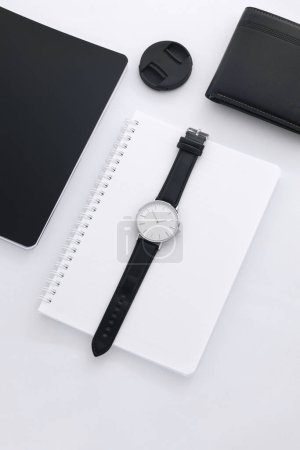 Foto de Reloj de cuero negro en escritorio blanco con cuaderno blanco y negro - Imagen libre de derechos