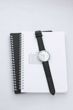 Photo for Black leather watch on white work desk with black and white notebooks - Royalty Free Image