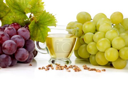 Foto de Aceite de semilla de uva sobre fondo blanco. La imagen también muestra uvas claras y uvas oscuras dispuestas sobre un fondo blanco - Imagen libre de derechos