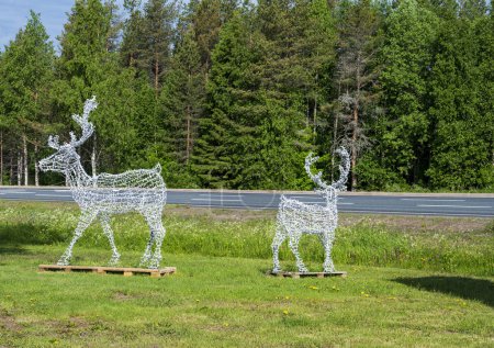 Photo for Two white wire reindeer on the grass near the forest - Royalty Free Image
