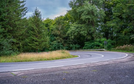 Empty asphalt road in beauty green forest with cloudy sky.