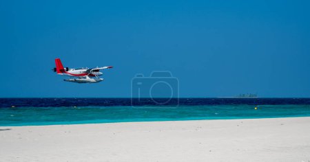 Téléchargez les photos : L'hydravion vole bas au-dessus du niveau de la mer par la plage de sable. Ciel bleu. - en image libre de droit
