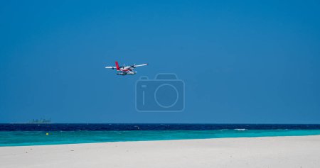 Téléchargez les photos : L'hydravion vole bas au-dessus du niveau de la mer par la plage de sable. Ciel bleu. - en image libre de droit