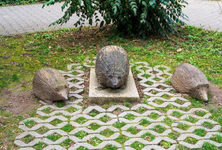 Brown wooden sculptures of hedgehogs on the grass.