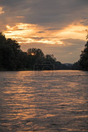 A sunset, the river Mura in nature with a cloudy sky