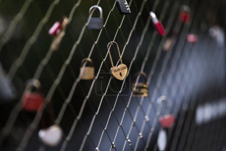 A heart padlock hanging on a bridge fence as a sign of love and romance.