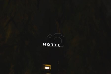 Téléchargez les photos : Un hôtel à Murska Sobota la nuit encadré par quelques branches aux feuilles vertes - en image libre de droit