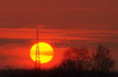 Une tour de radio à Gliwice contre le soleil couchant vu de loin (beau coucher de soleil pendant la journée d'été)