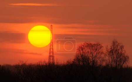 Une tour de radio à Gliwice contre le soleil couchant vu de loin (beau coucher de soleil pendant la journée d'été)