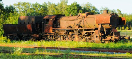 Eine alte Rostdampflokomotive, die im Sonnenuntergang auf dem Nebengleis steht (aufgenommen in Kaschubia in Polen))