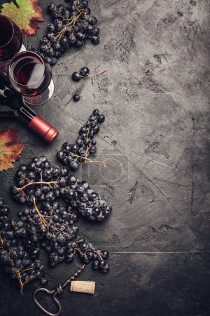 Téléchargez les photos : Vin avec raisins, feuilles et bouchons sur fond sombre, copyspace, plat - en image libre de droit