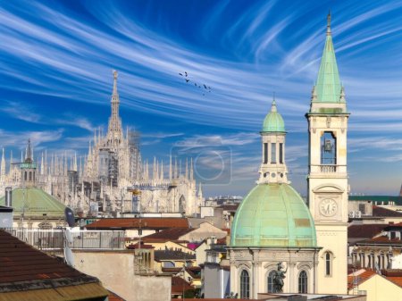 A serene Milan skyline with the Duomo di Milanos Gothic spires against a blue sky, historical buildings with green copper roofs, and birds in flight, reflecting the citys cultural heritage.