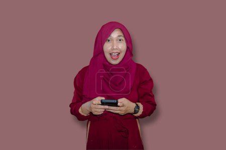 Photo for Portrait of Asian muslim woman using mobile phone against pink background - Royalty Free Image