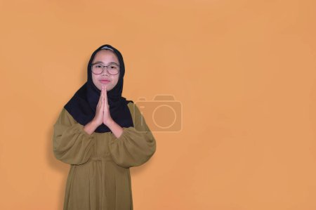 Photo for Portrait of Asian muslim woman praying on orange background with copy space - Royalty Free Image