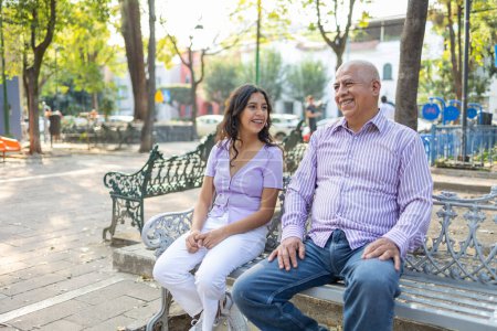 Photo for Grandfather and granddaughter smiling and talking while sitting in the park. High quality photo. - Royalty Free Image