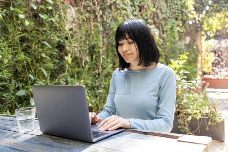 Photo for Portrait of beautiful young Asian woman using laptop at the bar. She is remote working - Royalty Free Image