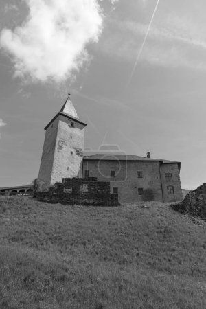 Iglesia medieval fortificada en Europa desde el fondo de la colina en blanco y negro.
