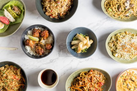 An overhead view captures a table brimming with an array of delectable Asian dishes. The rich and diverse flavors of Asian cuisine. High quality photo