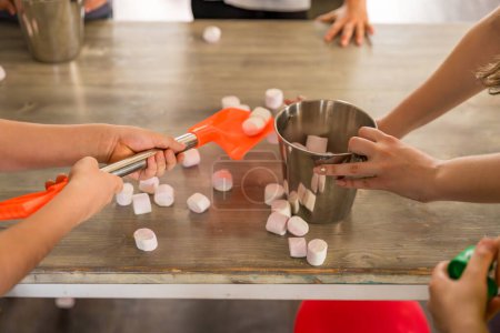 Playing with children: hands on the table with marshmallows, bucket and shovel. Animator for children. High quality photo