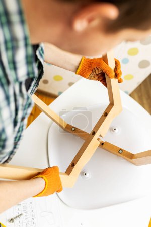 Photo for Self-assembly furniture concept. The young man himself assembling chairs. He uses tools for furniture - Royalty Free Image