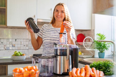 Photo for Young woman making carrot juice with juice machine at home kitchen. - Royalty Free Image