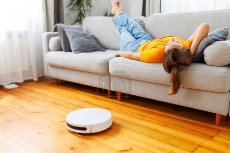 A woman peacefully sleeping on a cozy sofa while a robot vacuum quietly takes care of the cleaning. Serenity meets smart living