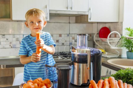 A smiling young boy prepares carrot juice using a juicer in a sunny kitchen.