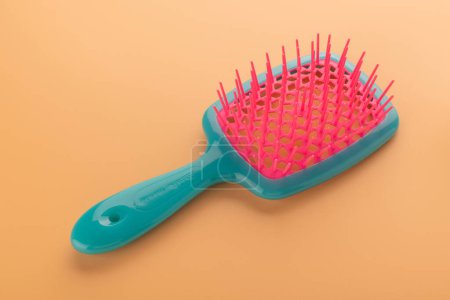 Eine lebendige Krickente und rosa Haarbürste isoliert auf einem warmen orangen Hintergrund, die Einfachheit und Hygiene betont.