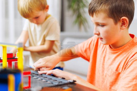 Two young boys concentrate on assembling colorful building blocks in a bright, cozy room.