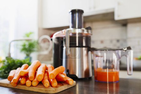 A kitchen scene with fresh carrots on a cutting board and a juicer filled with carrot juice, highlighting healthy lifestyle choices.