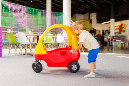 Young boy pushing a toy car in a vibrant indoor play area