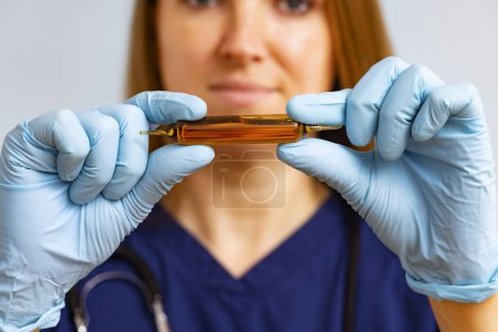 Trabajador sanitario enfocado sosteniendo una ampolla de vidrio con medicación cuidadosamente.