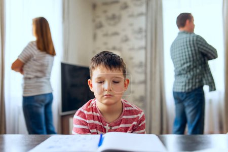 Young Boy Studying with Parents Arguing in Background.