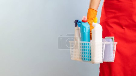 Close-up of cleaning supplies in a basket held by someone in an apron